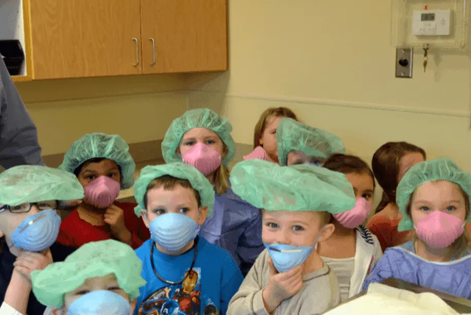 Children wearing masks and playful doctor caps during a veterinary field trip at Lakewood Animal Hospital